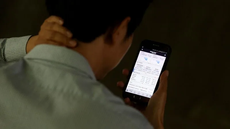 급변장에 투자자가 스마트폰과 노트북으로 주문 상태를 확인하는 장면